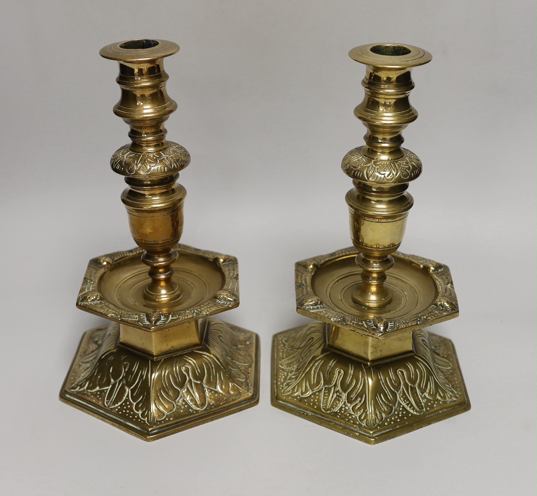 A pair of 19th century Scandinavian candlesticks, each with hexagonal domed bell base cast with acanthus, hexagonal mask cast drip tray and vase knopped stem, 28cm